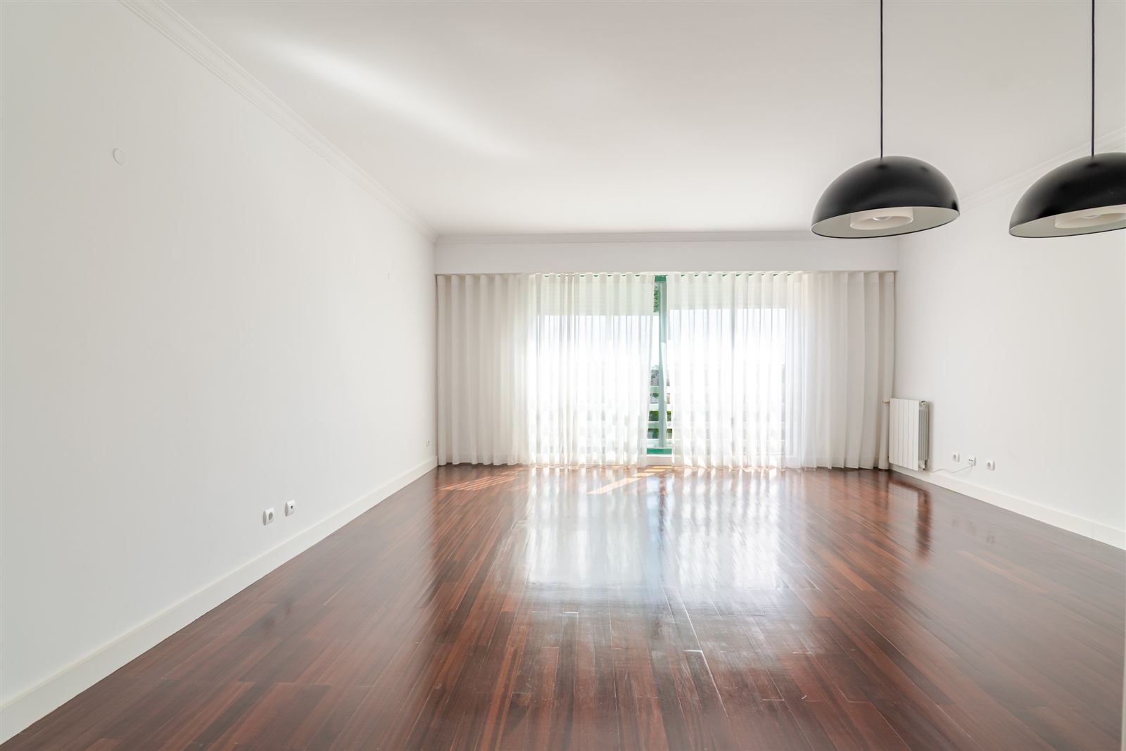 Sala ampla com soalho em madeira maciça e janelas para poente
